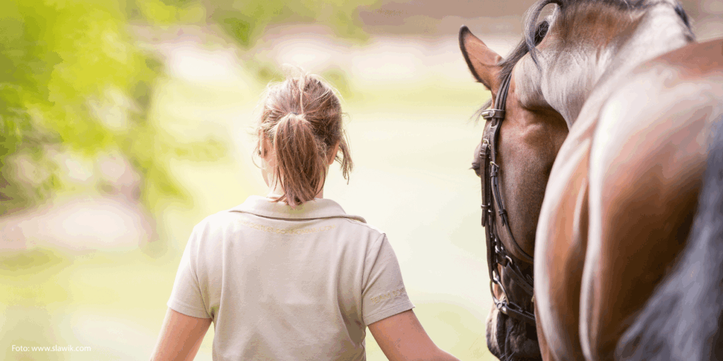 Ansicht von hinten: Frau führt Pferd